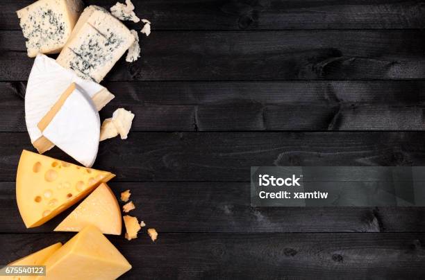 Different Types Of Cheese On Black Wooden Table Top View Stock Photo - Download Image Now