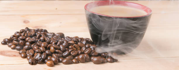 Cup of coffee on a wooden table with coffee grains and sugar