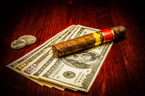 istock Cuban cigar on a several dollar bills and also coins on the table 675553028