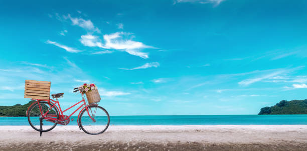 青い海の上の白い砂浜に赤いヴィンテージ自転車と澄んだ青空の背景、春または夏の休暇の概念。 - bald head island ストックフォトと画像