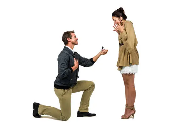 Man offering engagement ring to partner against white background