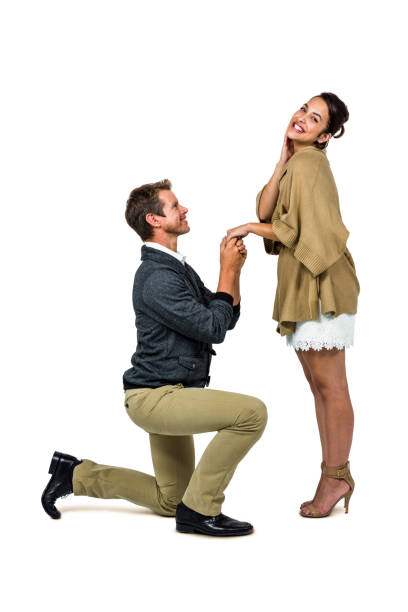 istock Man proposing woman while kneeling and holding hands 675570394