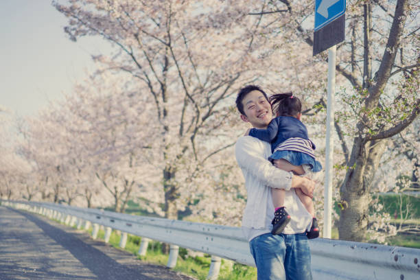 istock Father and daughter having fun time in cherry blossoms. 675576740