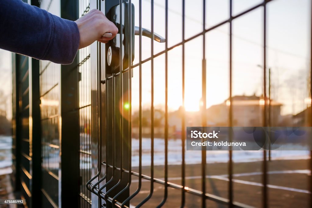 person wants get in on playground through the little gate of welded wire mesh person wants get in on playground through the little gate of the welded wire mesh, wonderful winter sunny day Fence Stock Photo