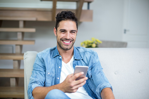 Portrait of smiling smart man using smartphone at home