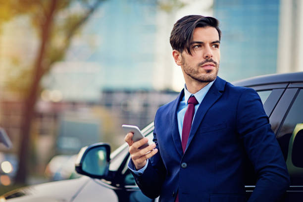istock Businessman is texting next to his car 675606408