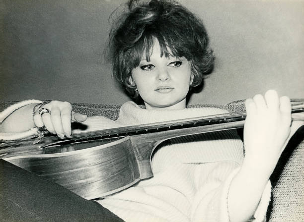 Young woman from the sixties playing guitar Vintage black and white photo from the sixties of a young woman playing guitar. string instrument photos stock pictures, royalty-free photos & images