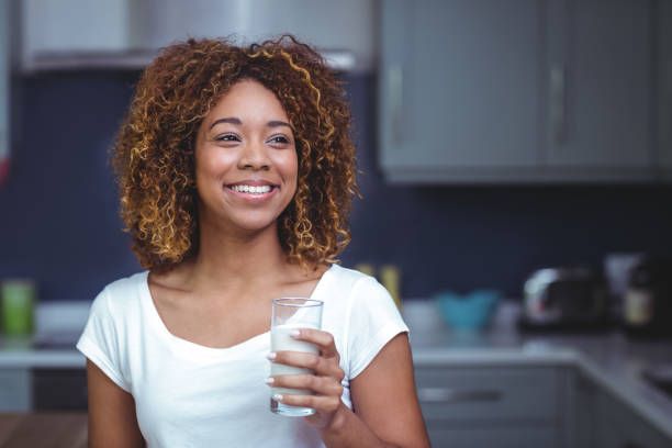 sonriente joven mujer sosteniendo el vaso de leche - mujer bebiendo leche fotografías e imágenes de stock