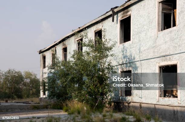 Burnеd Light Blue Twostoreyed Building With Green Trees After Fire Stock Photo - Download Image Now