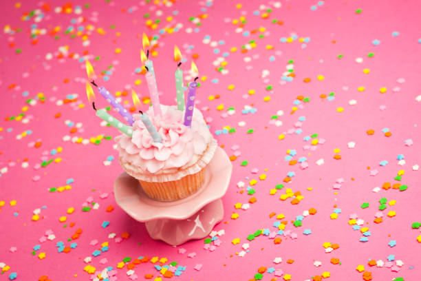 istock Birthday Cupcake with Candles and Confetti on Pink Background 675652982