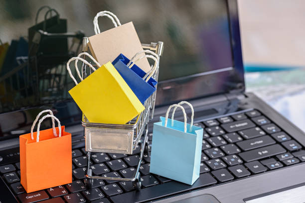 Five paper shopping bags and a shopping cart on a laptop keyboard. Five paper shopping bags and a shopping cart on a laptop keyboard. Concept about online shopping that customers can buy everything from home or office and the messenger will deliver to the doorstep. hoax stock pictures, royalty-free photos & images