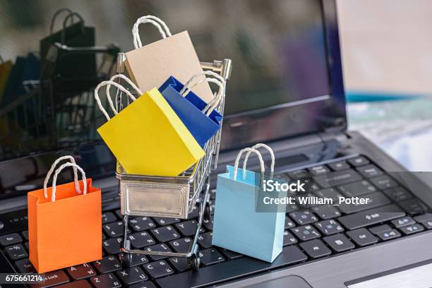 Five Paper Shopping Bags And A Shopping Cart On A Laptop Keyboard Stock Photo - Download Image Now