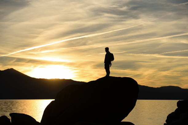 istock A Man Hiking on Rocks Overlooking a Lake at Sunset 675664980