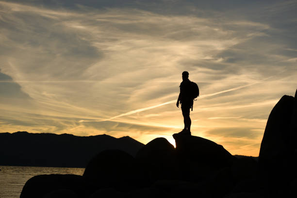 istock A Man Hiking on Rocks Overlooking a Lake at Sunset 675664982