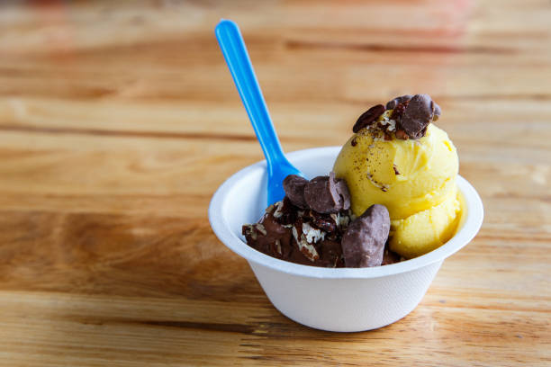 istock Scoops of mango ice cream with nut and chocolate, in blank takeaway paper cup 675665166