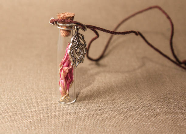 istock Glass small bottle with a pink flower inside on a canvas 675666258