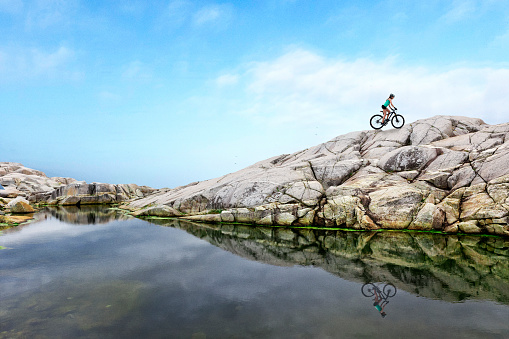 Woman on mountain bike riding up rock face hill in Nova Scotia