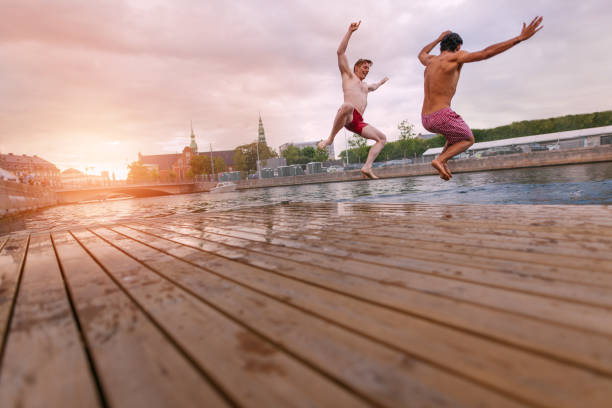 istock Young people jumping into lake in city 675683998