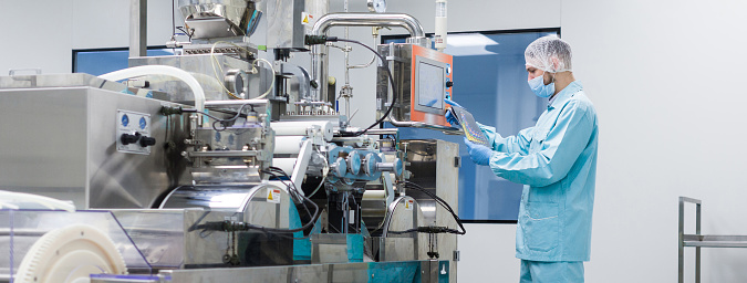 widescreen picture, caucasian scientist in blue lab suit trying to fix manufacture machine with shafts in clean factory