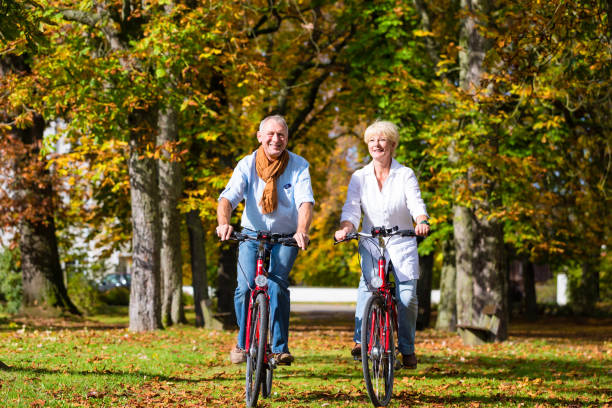 пожилые люди на велосипедах, имеющих тур в парке - falling people tripping senior women стоковые фото и изображения