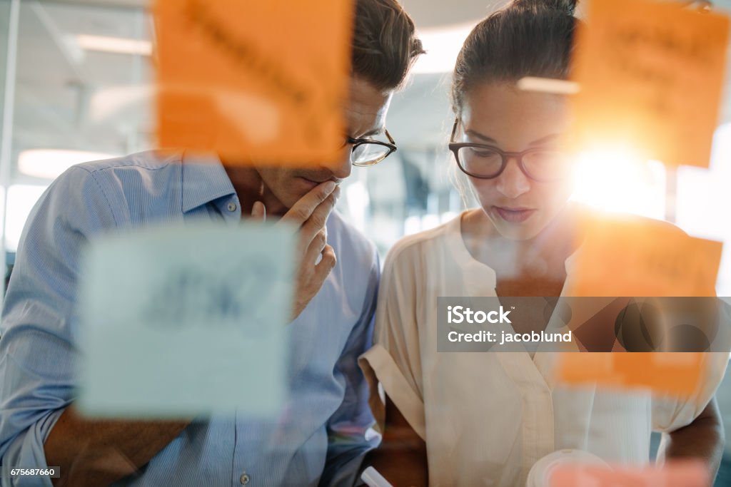 Des professionnels se tenait derrière la paroi de verre avec les notes collantes - Photo de Bureau - Lieu de travail libre de droits