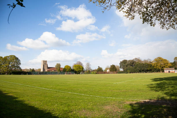 Quiet Suffolk quaint traditional village playing field in spring sun with clouds
