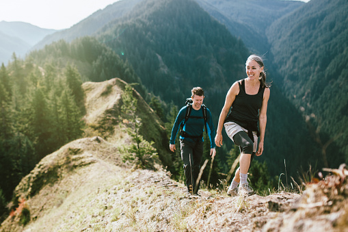 A fit man and woman in their 50's hiking the trail on a mountain ridge, the beautiful Columbia river gorge spreading out behind them. They smile, enjoying the exercise, the beauty of nature, and the joy of life.  Horizontal image with copy space.
