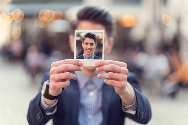 istock Young man holding instant photo in front of his face 675700856