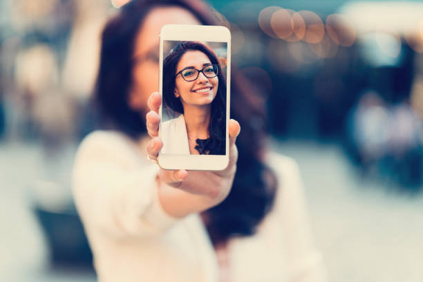 mulher mostrando selfie tirada com celular para a câmera - pessoas fotos - fotografias e filmes do acervo