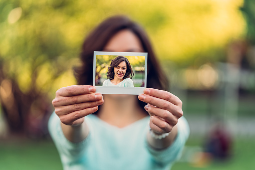 Young woman showing instant print photo to the camera