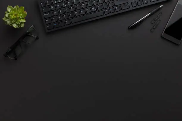 Photo of Top view of black office desk with computer and supplies