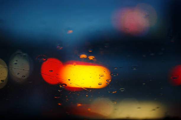 Rain drops on car glass with traffic light , focus on raindrops.