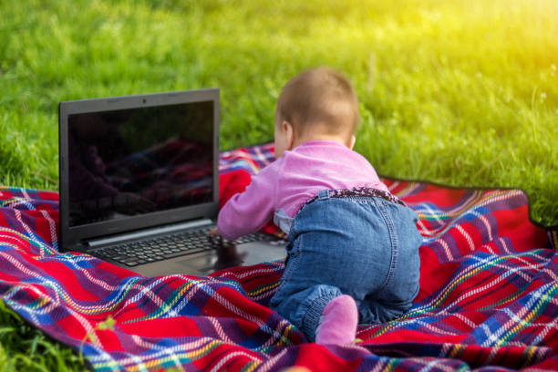 cute baby girl playing with laptop outdoors on green grass. - child prodigy imagens e fotografias de stock