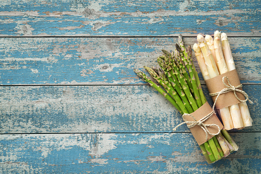 Fresh green and white asparagus with strawberries on wooden background