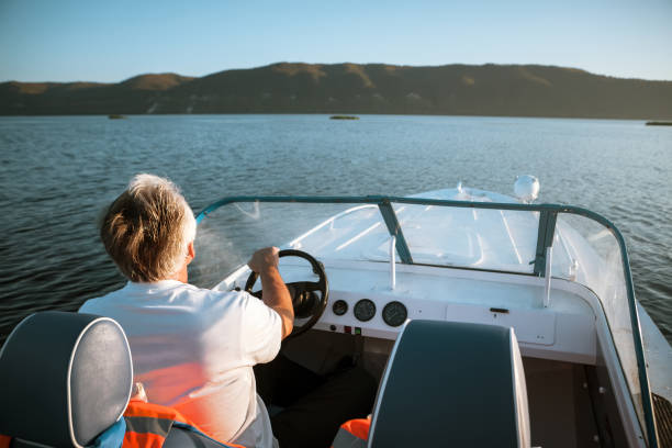 homme d’âge mûr conduisant un hors-bord - motorboat nautical vessel speedboat lake photos et images de collection