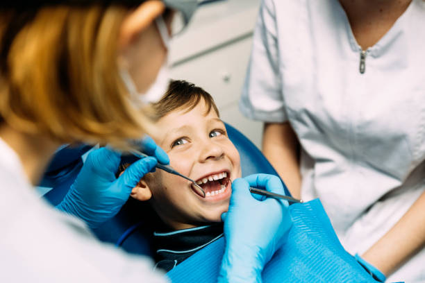 dentistas con un paciente durante una intervención dental al niño. - dentists chair fotos fotografías e imágenes de stock