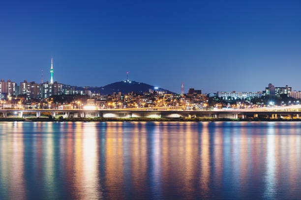The modern cityscape and skyline of Seoul with famous with N Seoul Tower in the distance reflecting in the Han River. View from Banpo Hangang District at twilight towards the Han River Skyline. Banpo Hangang, Seoul, South Korea.