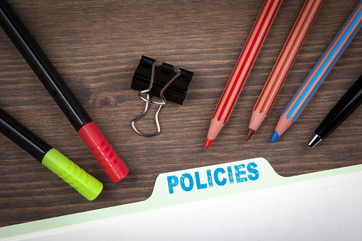 Policies Concept. Folder Register on a dark wooden desk.