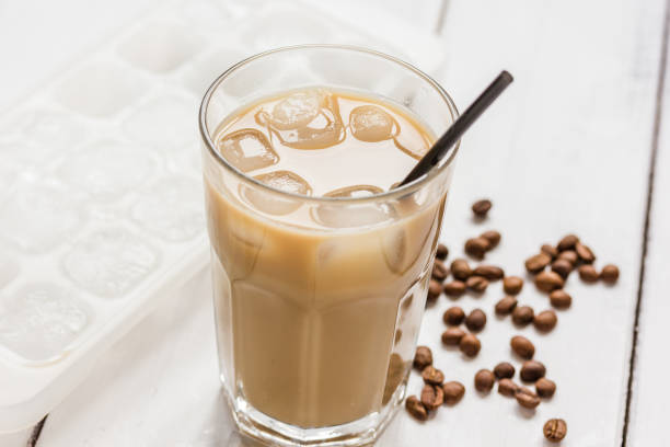 istock cold coffee glass with ice cubes on white table background 675746828
