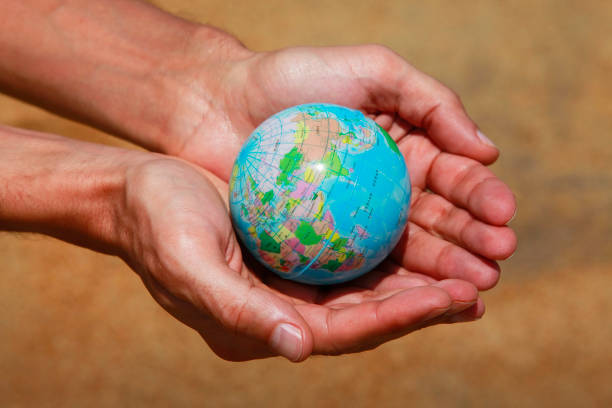 istock Male hands with the small globe on a background of sand 675767740