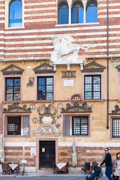 Verona: people near facade of Palazzo della Ragione on Piazza dei Signori in Verona city in spring. The construction of Palazzo della Ragione began in 1193 year