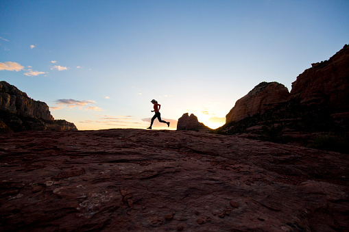 A woman runs a popular trail at the end of the day in Sedona, Arizona, USA.