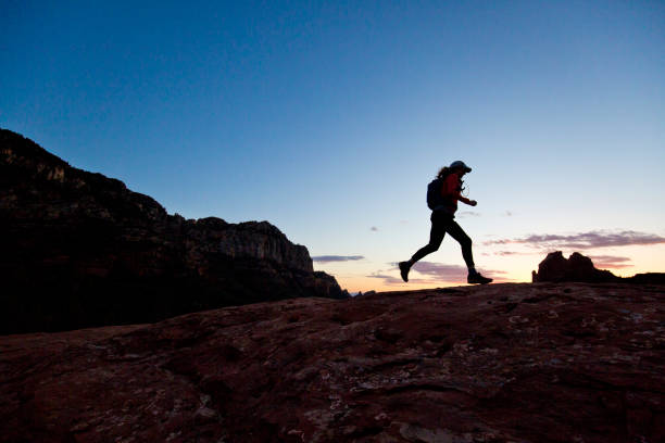 A woman goes for a cross-country trail run at sunset in Sedona, Arizona, USA. stock photo