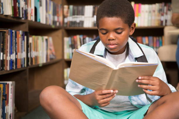 istock African descent boy in school library reading book. 675785688