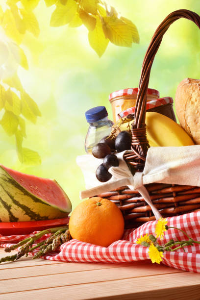 istock Picnic wicker basket with food on table in field vertical 675790978