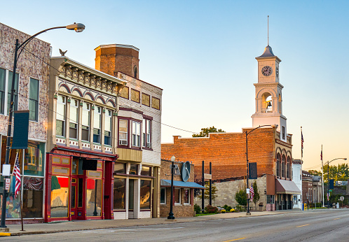 The main street of a quaint, classic small town located in midwestern America with storefronts and a clock tower