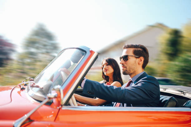 junge modische paar in einem oldtimer-cabrio-sportwagen - outdoors car convertible wealth stock-fotos und bilder