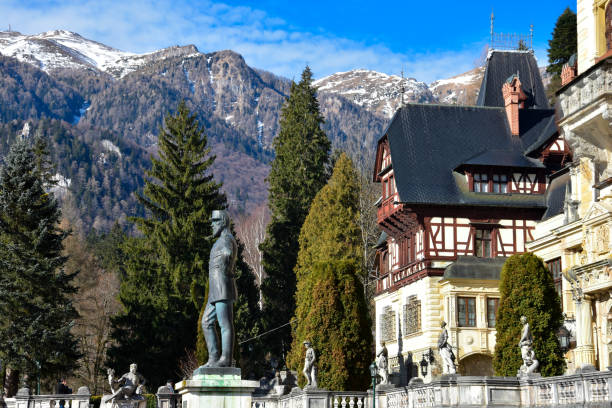 Sinaia, Romania. February 04, 2017. Statue of King Carol I. Peles Castle Gardens on a sunny winter day (Castelul Peles). Carpathian Mountains on the background