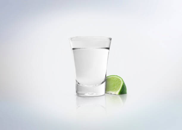 Silver shot of tequila. Alcoholic distilled beverage with slice of lemon / lime on the side. Isolated on white background. tequila slammer stock pictures, royalty-free photos & images