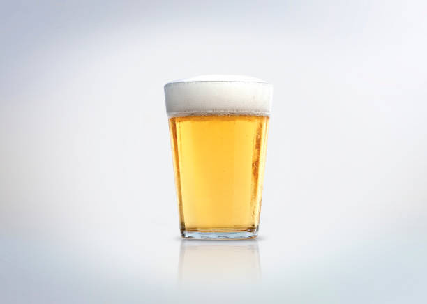 Glass of light lager beer with foam. Isolated on white background. glass of beer stock pictures, royalty-free photos & images